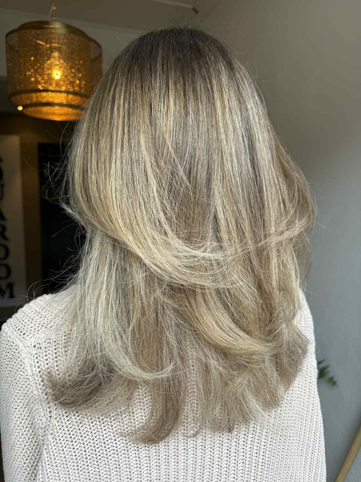 Blont h&aring;r i golden pearl-ton med dimension, nyansering och s&ouml;ml&ouml;sa layers.